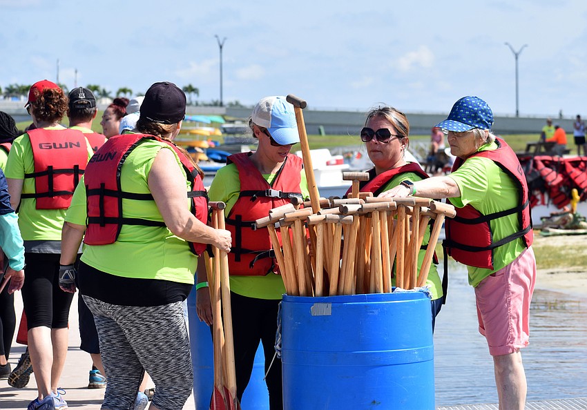 Members of Dragon Flys grab paddles before heading to their boats.