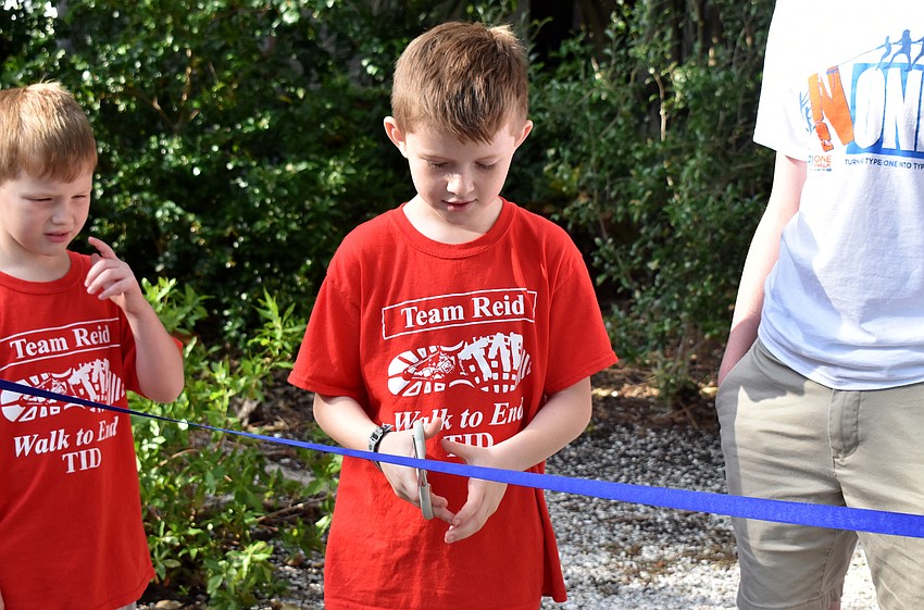 Reid Kennedy cuts the ribbon to start the walk.