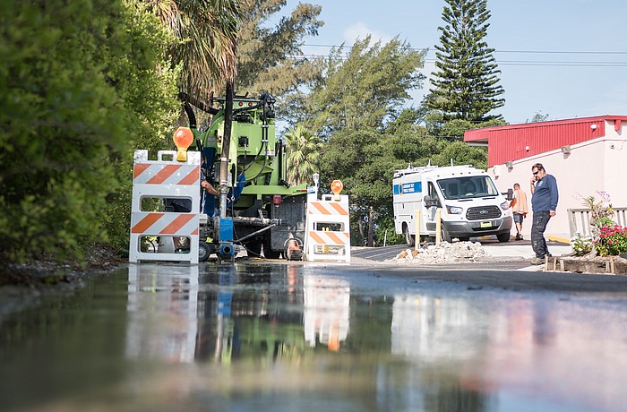 Workers tend to the water system along St. Judes Drive on Sunday following the pipe break the night before.