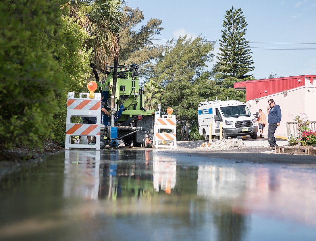 Workers tend to the water system along St. Judes Drive on Sunday following the pipe break the night before.