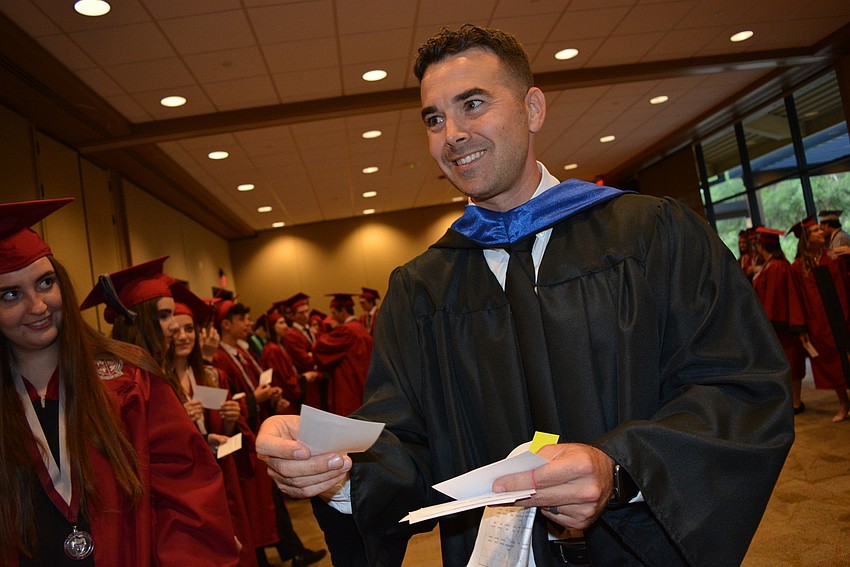 Social studies teacher Thomas Bellantonio hands out name cards to senior for the ceremony.