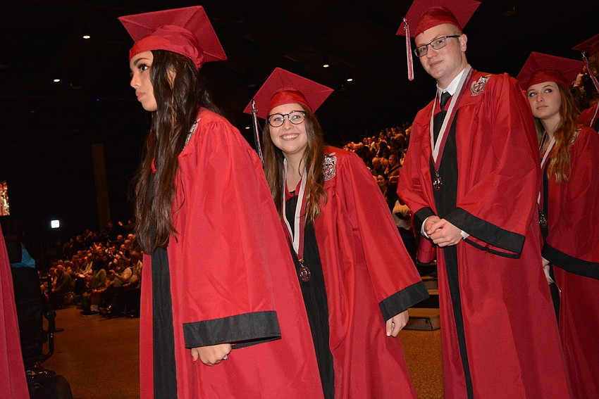 Mary Bolles, center, is all smiles as she sees her family in the bleachers as she walks into the auditorium.
