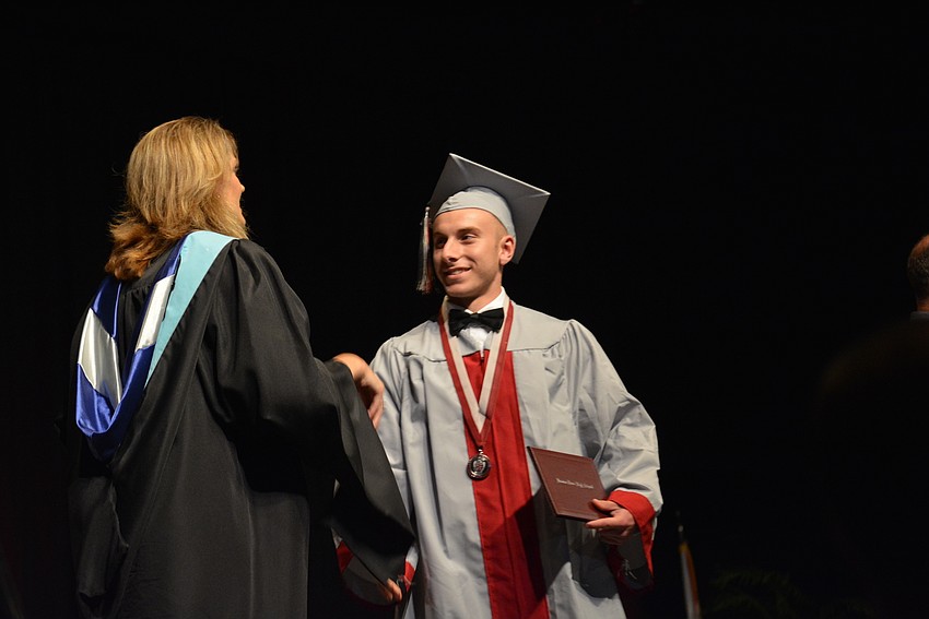 Principal Sharon Scarbrough congratulates Kyle Nichols and then moves his tassel. Nichols graduated in the top 10% of his class.