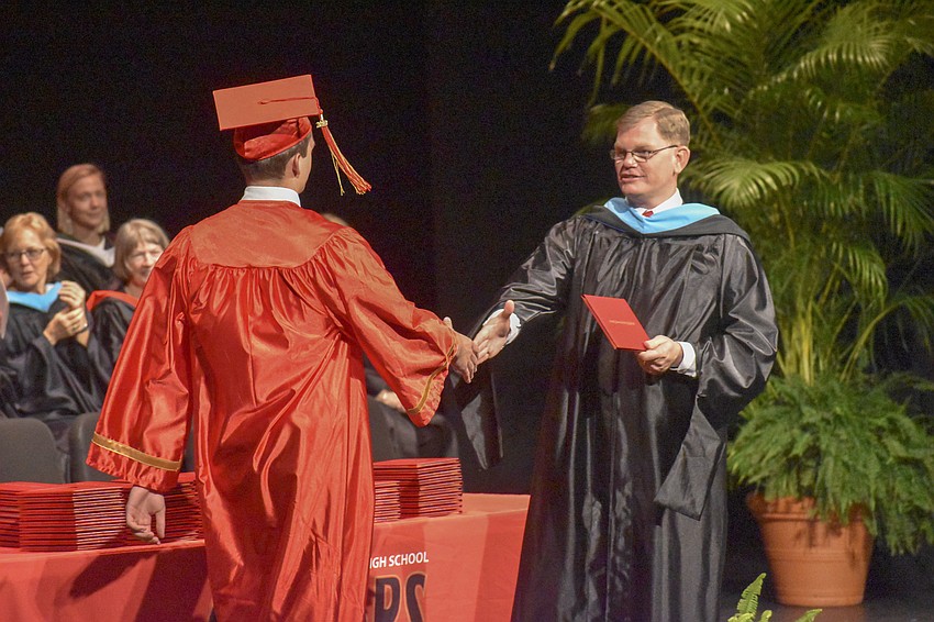 Principal Ben Hopper shakes the hand of a senior as he walks across the stage.