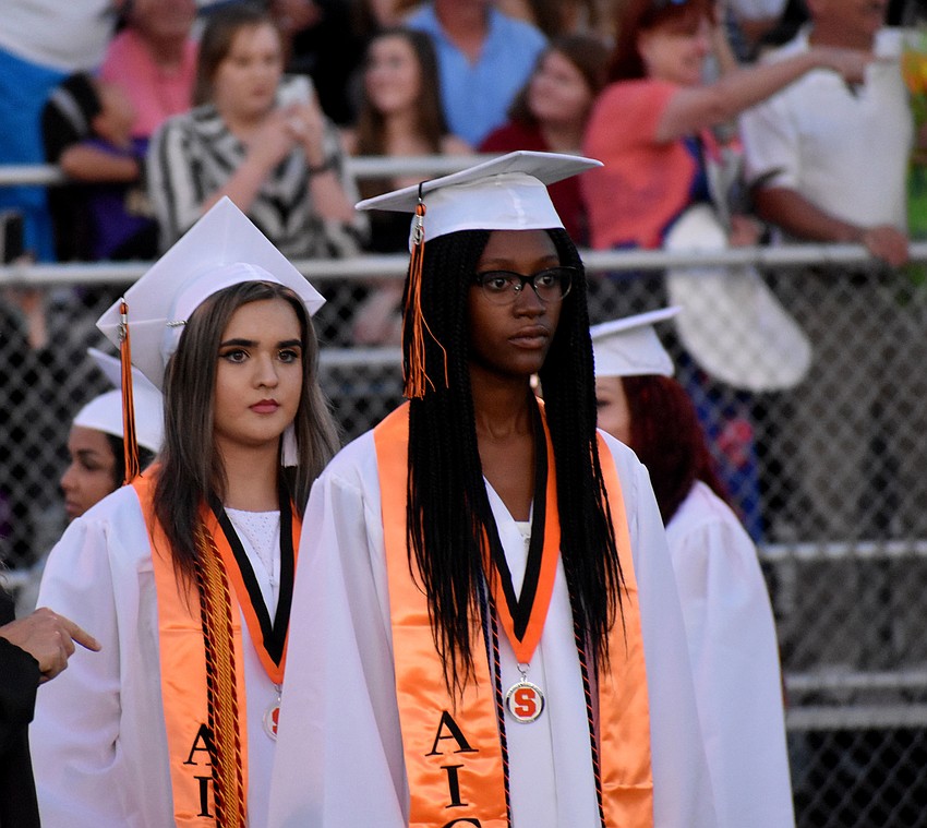 Graduates wait for their turn to cross the field.