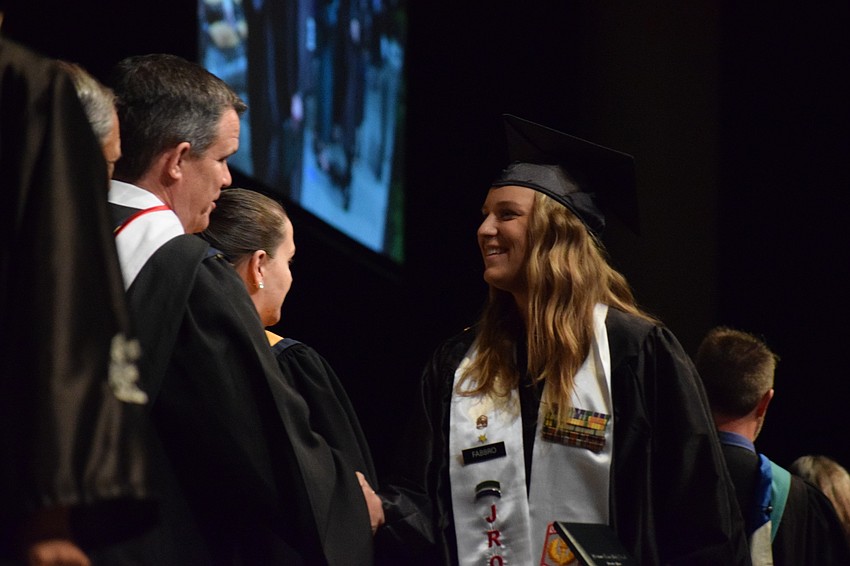 Graduate Madison Fabbro shakes hands with school board member Charlie Kennedy.