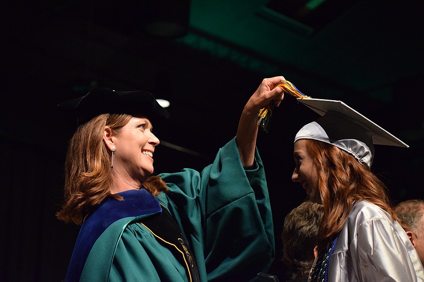 Assistant Principal Melinda Lundy moves the tassel on the cap of Mary Grace Epps.