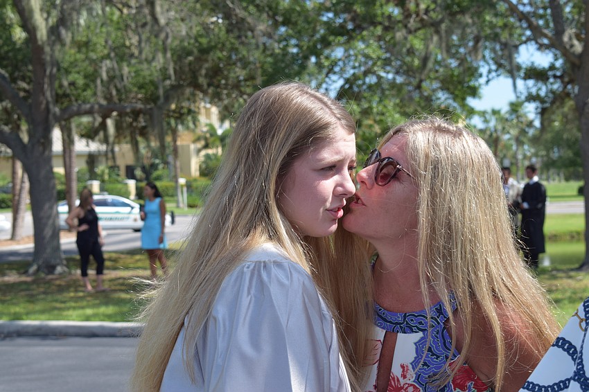 Robyn Richards leans in to kiss her daughter, Emily Richards, on the cheek after the latter's graduation.