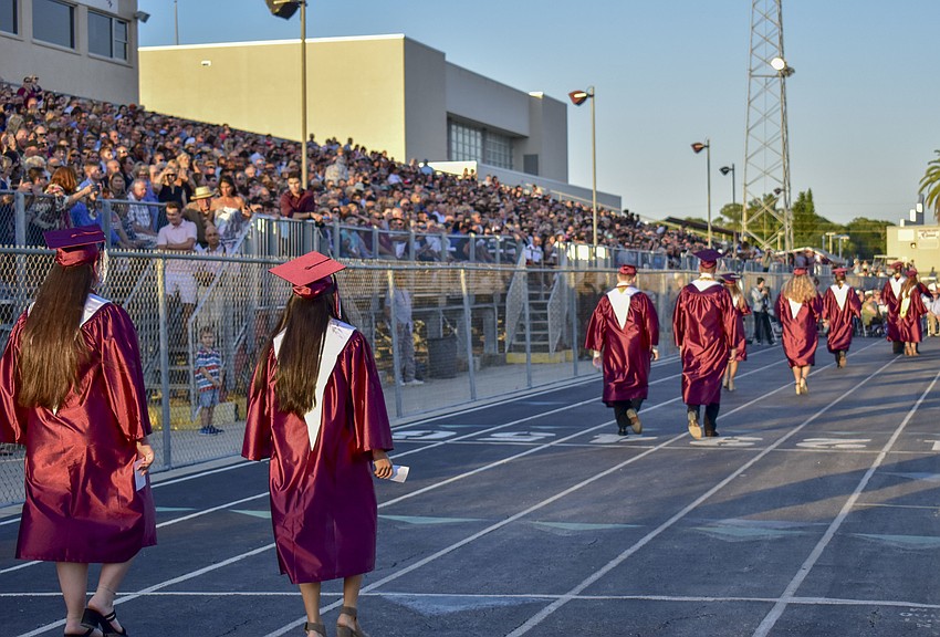 Graduates walk two by two to their seats.