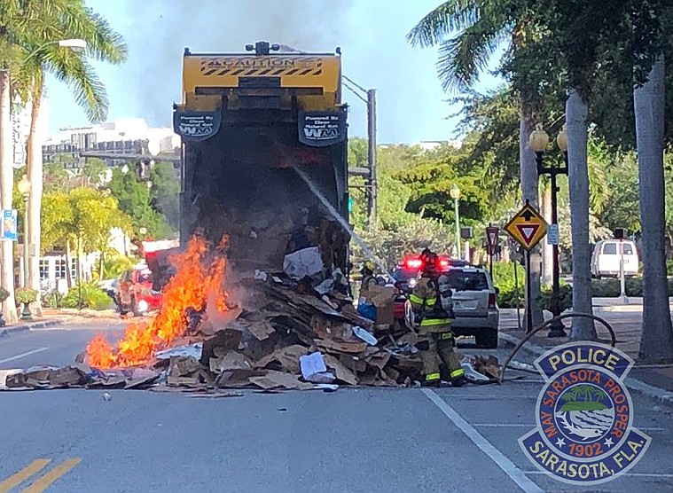 (Sarasota Police Photo) Firefighters work to extinguish the flames of a recyclable-collection truck in the Fire Points area of downtown this morning.