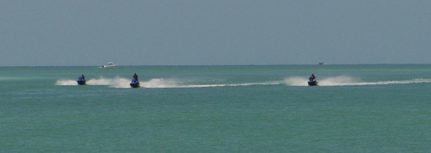 Personal watercraft riders enjoy the shallow waters nearby.