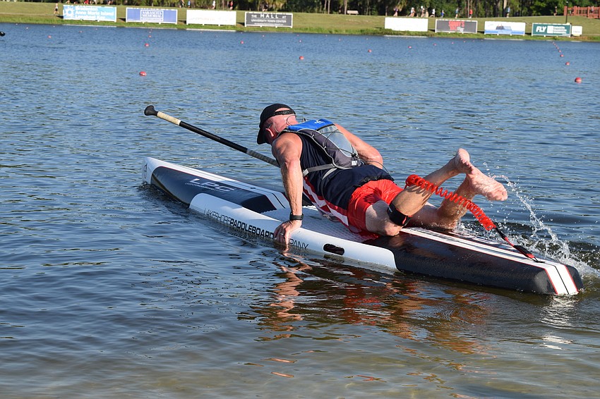 A paddle boarder mounts his board before standing up and beginning the second half of the race.
