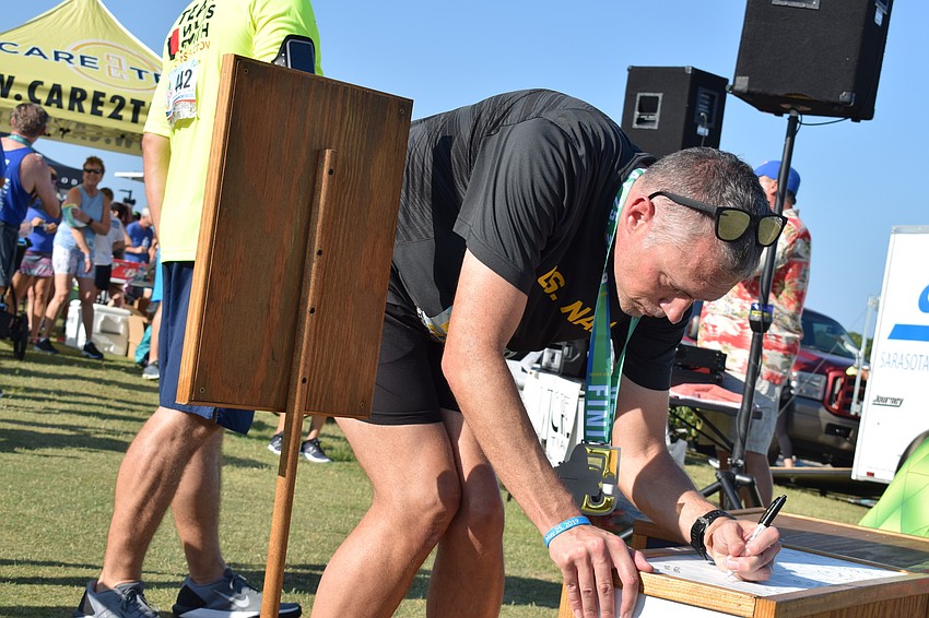 David Webber, of Tampa, signs a podium along with other veterans and service members. Webber said he is a commander in the Navy.