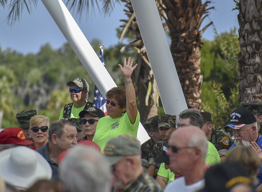 Volunteers we placed flags at the fallen soldiers' graves are asked to stand and raise their hands.