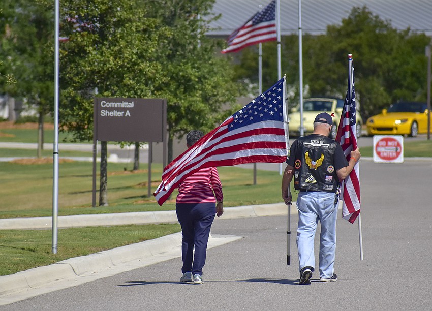 A couple walks to the gravesites with American Flags.