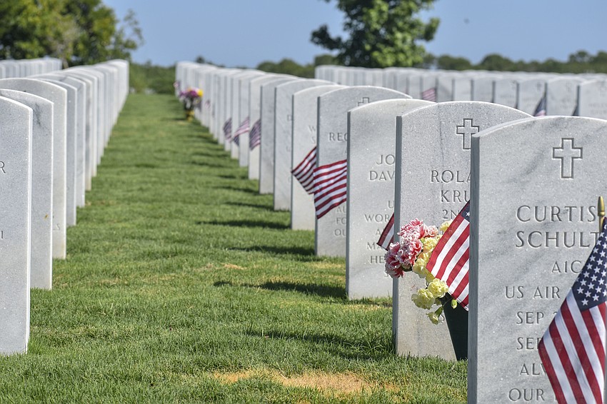Flags and flowers line the graves of fallen soldiers.