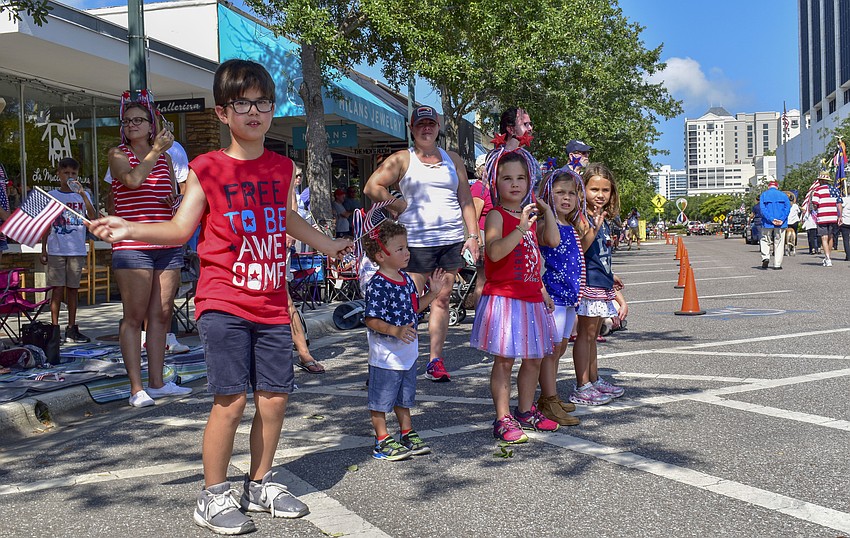 Children decked out in red, white and blue watch the parade as it goes by.