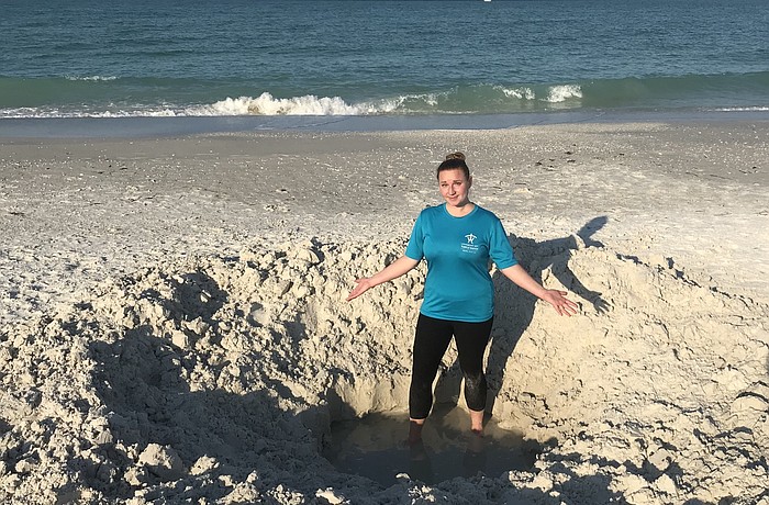(Courtesy photo) Longboat Key Turtle Watch volunteer Amanda Roth helps show perspective of the hole discovered Tuesday morning near the Broadway Street Beach Access.
