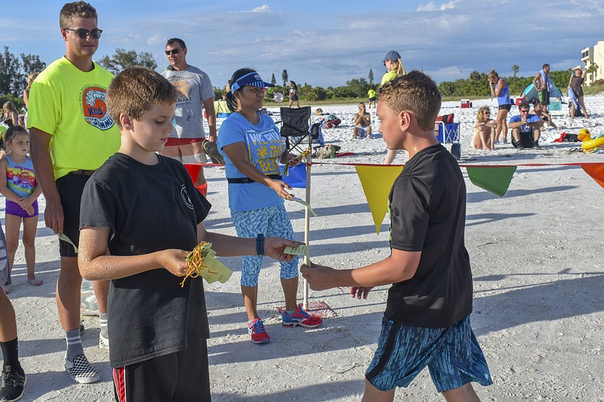 Bryce Hendrick (left) passes a ribbon to a participant.