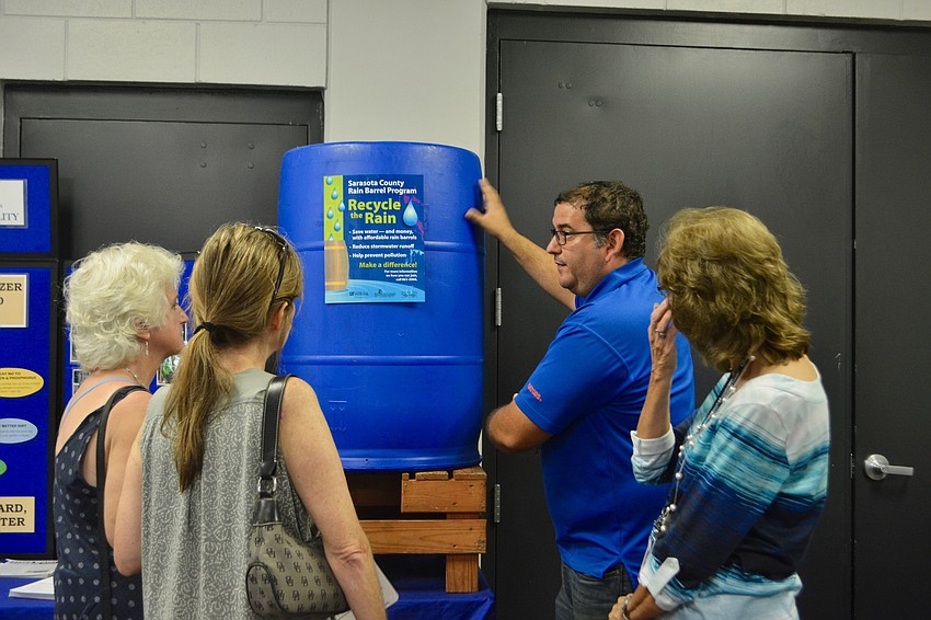 David Puoso, who works for the county's air and water quality department, shows attendees how a rain barrel works
