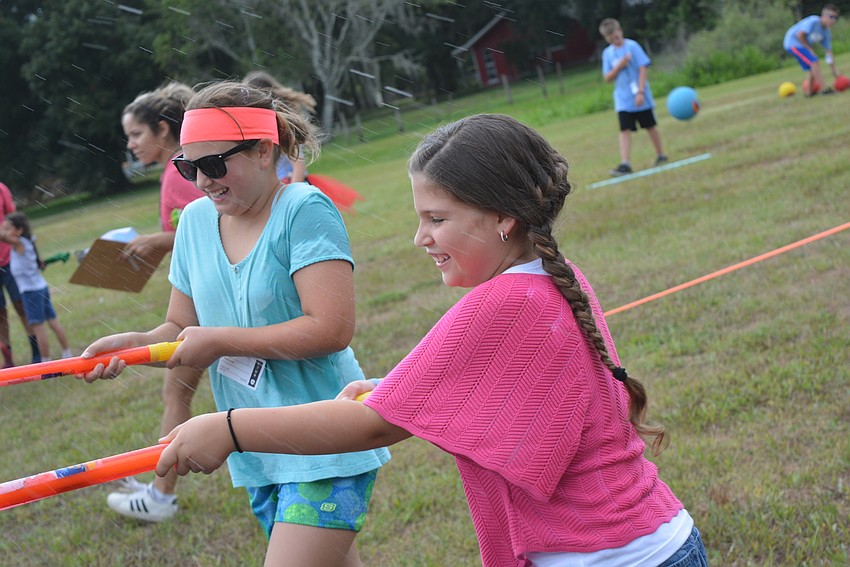Ten-year-old Bella Cox and  9-year-old Megan Fader squirt friends on the sidelines as they finish an obstacle course.