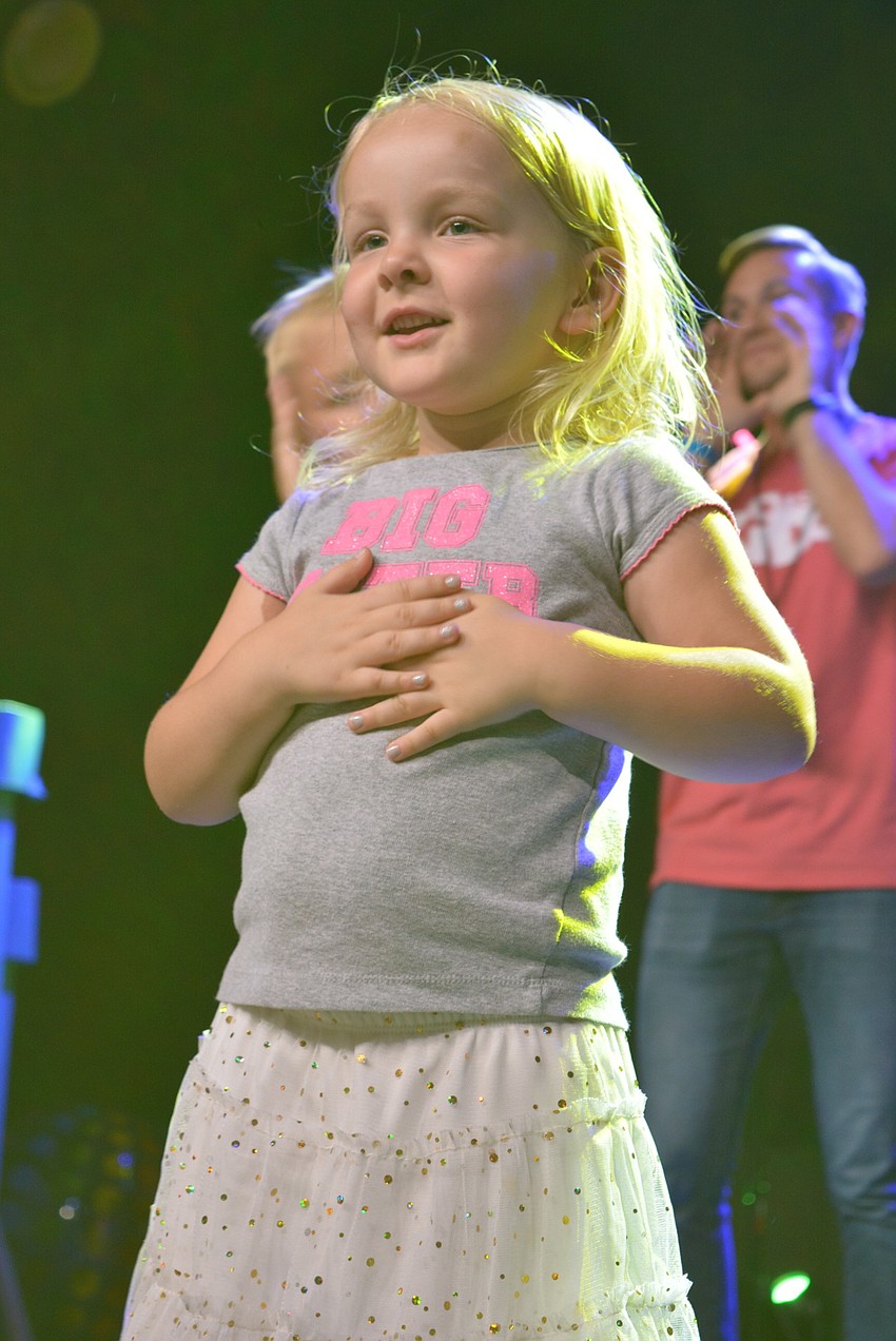 Lilah Peel, 4, is all smiles as she sings a song on stage with the other preschoolers.