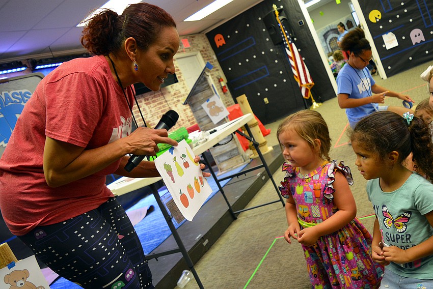 Teacher Josephine Ortiz teaches preschoolers Stella McCoy and Anna Sak about the 
