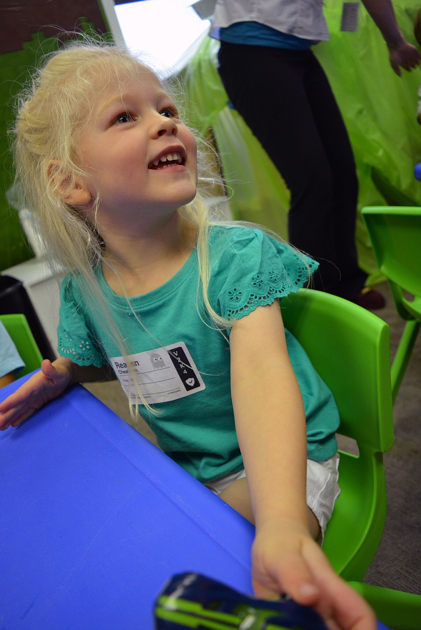 Three-year-old Reagan Cheatham plays with her race car as she awaits a snack of fresh fruit.