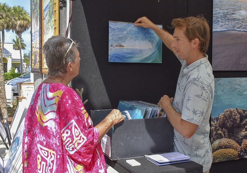 Jimmy Chadsey, a landscape photographer, (right) shows Patricia Watts one of his surf photographs.