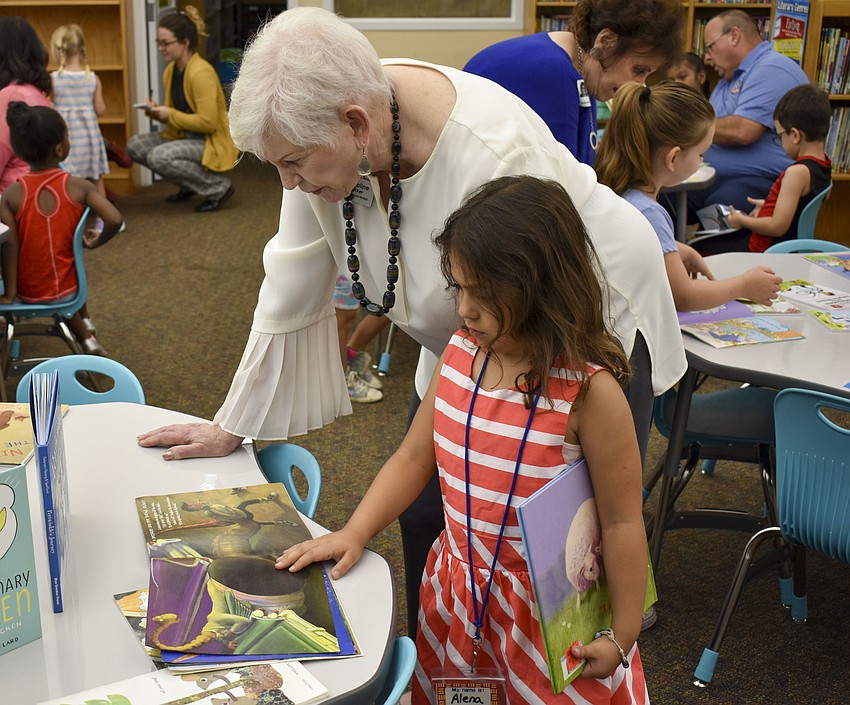 Caroline Zucker, vice chair of the School Board, helps Aleha Alicea read her new book.