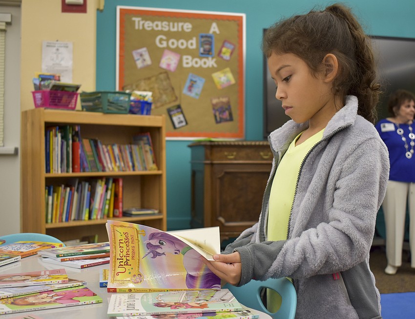 Maydee Cisneros,7, flips through a book from the 