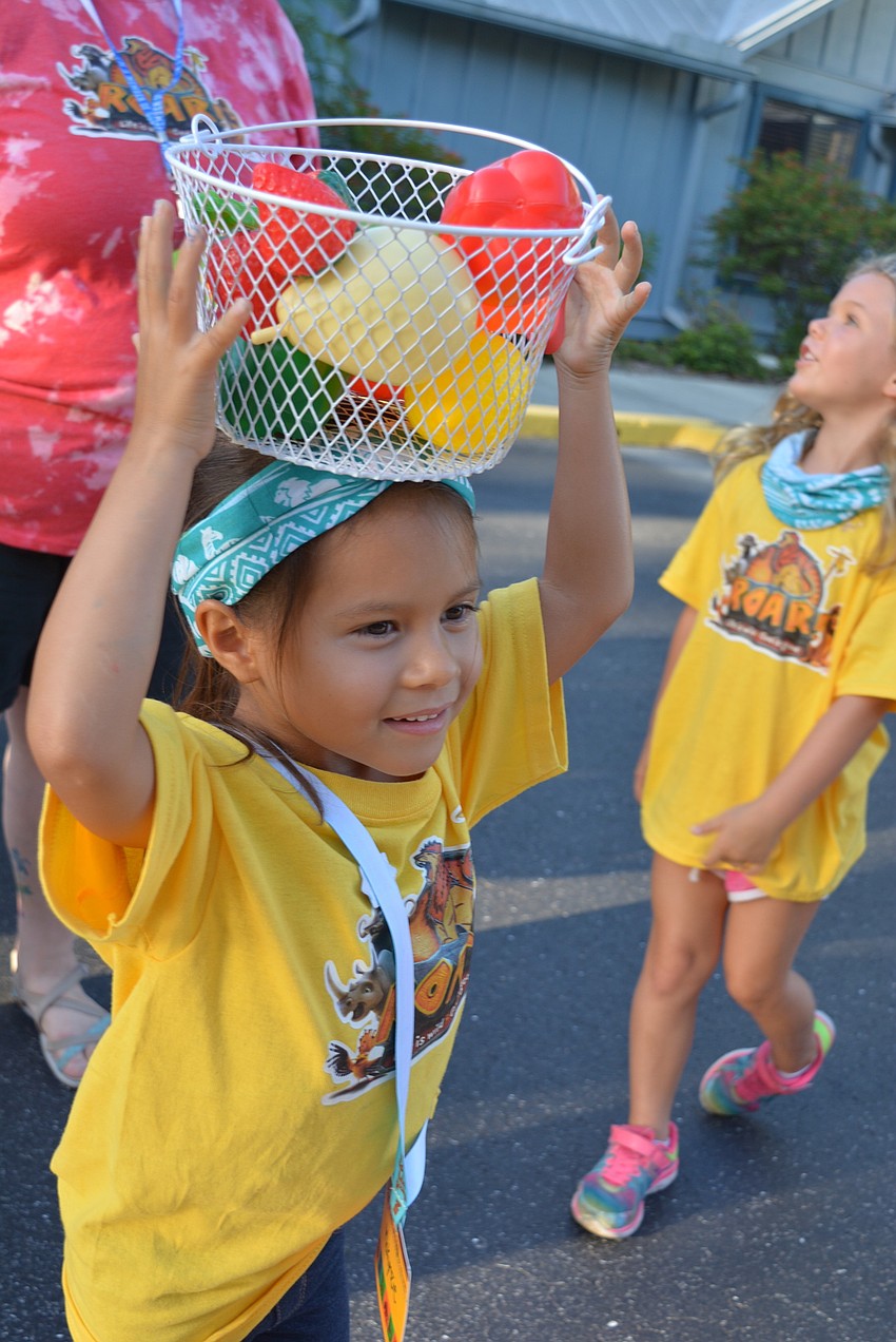 Makynzie Birch, 5, tries to balance a bucket on her head. She jumped up and down when her friends were successful doing it.