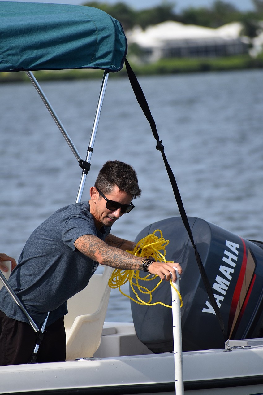 Nate Falcone measures the water depth before checking its clarity near Longboat Key.