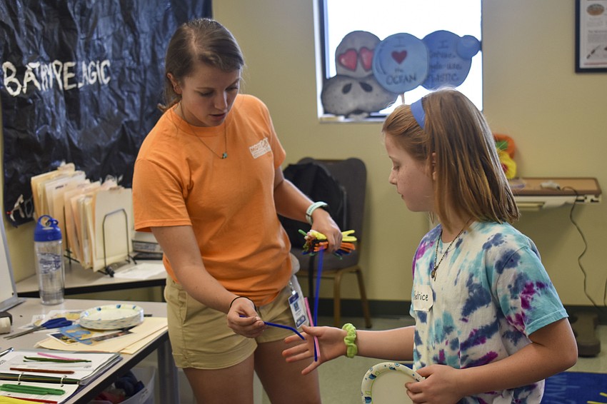 Kailey Bissell, a Mote education specialist, passes a pipe cleaner to Beatrice Bradburn.