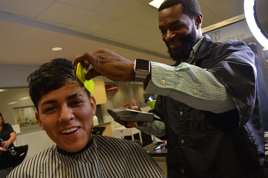 Manatee Technical College barbering and cosmetology student Brian Gutierrez gets a hair cut from his teacher, Aric Youmans.