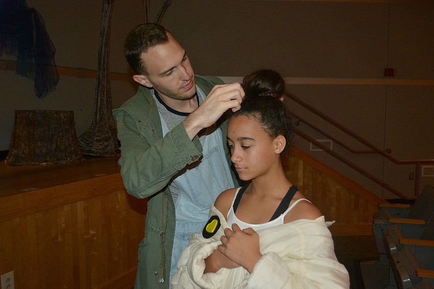 Music director Joseph Grosso fixes the hair of Yaira Spears who plays Olaf.