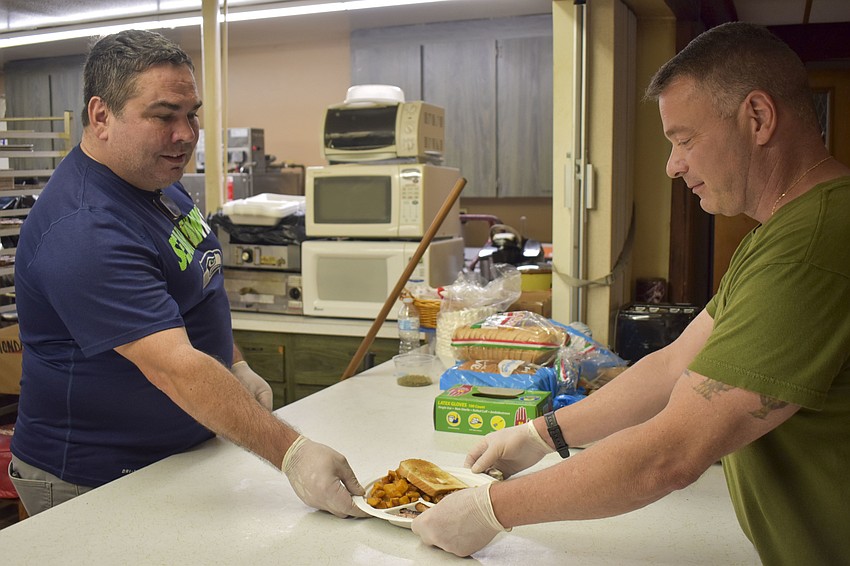 Greg Miller (left) passes off a plate to be delivered to the guests.