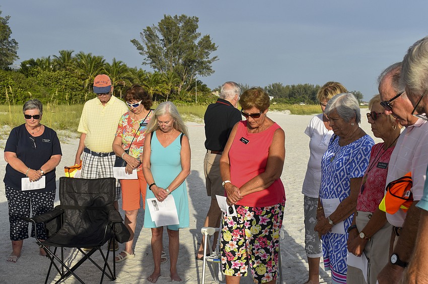 The church members bow their heads in prayer.