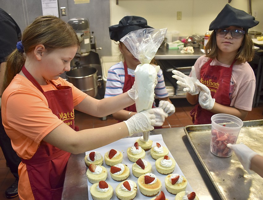 Sarah Gray pipes whipped cream on personal cheesecakes.
