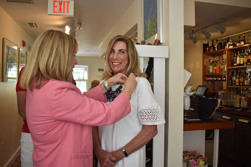Outgoing president Susan McGuire attaches a pin to incoming president Nancy Rozance's dress.