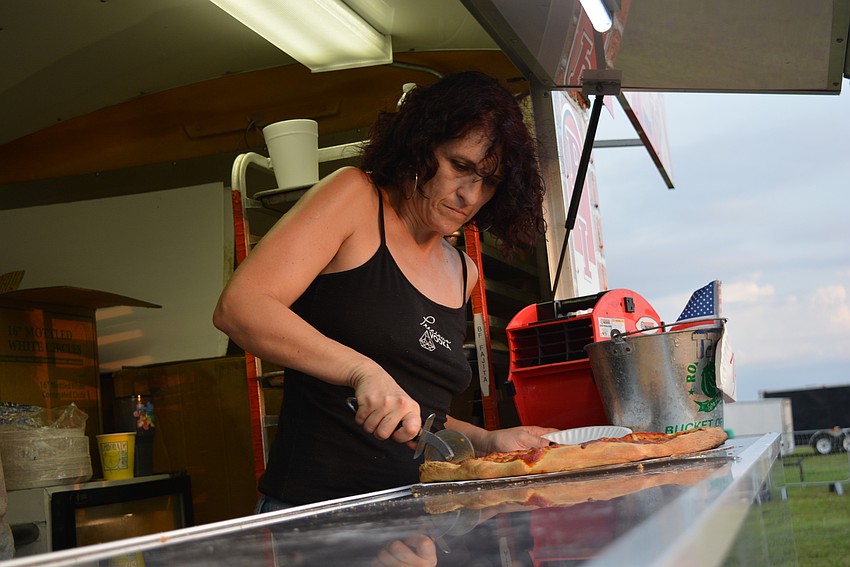 Kelly Cline slices up a hot cheese pizza for guests at Custom Catering's pizza food truck.