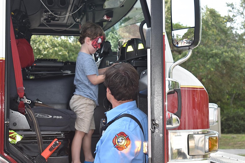 Ayden McCormick, AKA Spiderman, explores the firetruck as firefighter Brian Kolesa helps kids up into it.