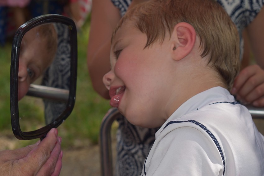 Grant Drake sticks his tongue out at himself after getting a snake painted on his arm.