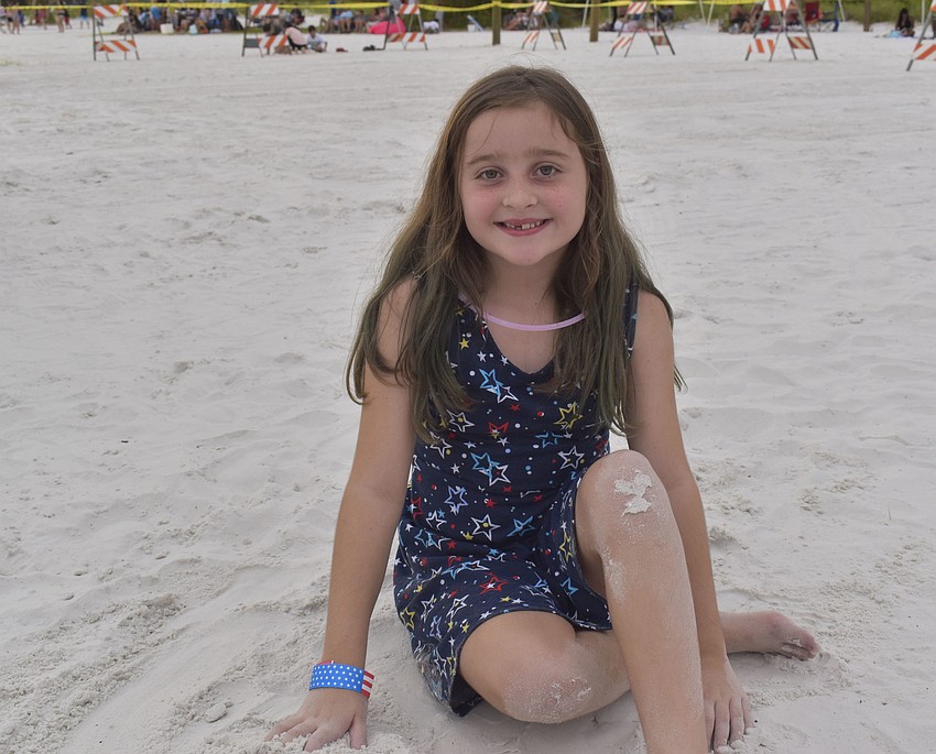 Madison Miliam, 7, lounges in the sand before the fireworks begin.
