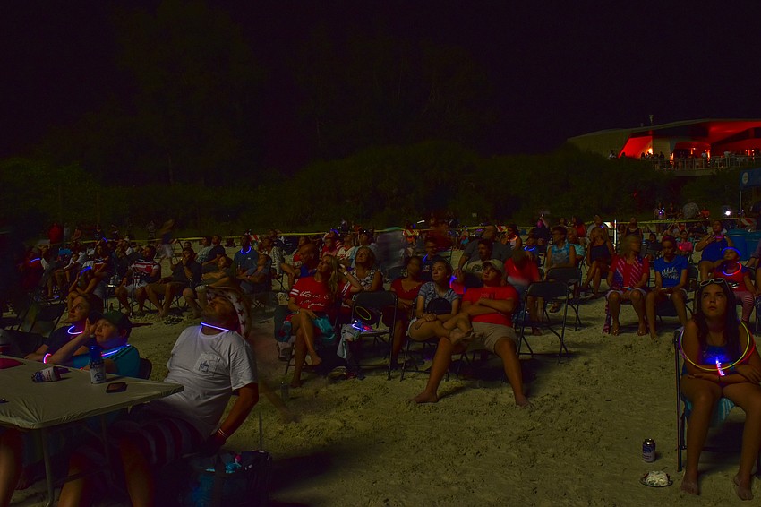 The crowd watches as the fireworks go off.