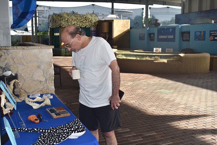 Roy Barzel checks out shark artifacts with a cup of coffee.