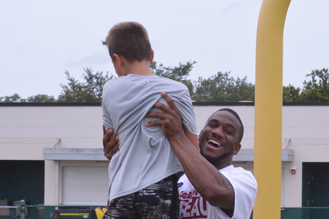 Evan Larrick, 9, is hoisted by Fabian Moreau after winning the 40-yard dash for his age (8-9 division).
