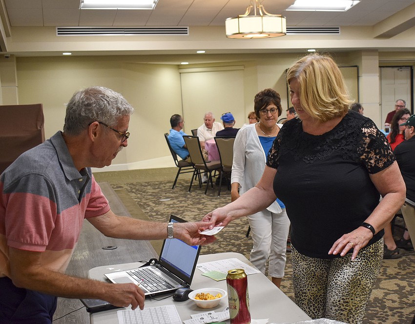 Kathy Docks passes her teams answer to emcee Bob Meisel.