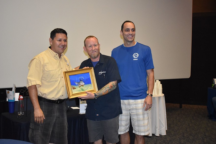 Part of winning chef Steve Phelps' (center) prize was a painting donated by artist Carlos Cardenas (left).