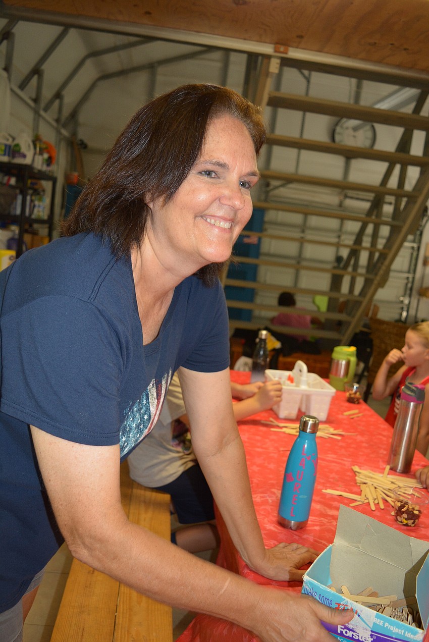 Camp organizer Maureen Hudson shows campers the craft of the day — a picture frame made from popsicle sticks.